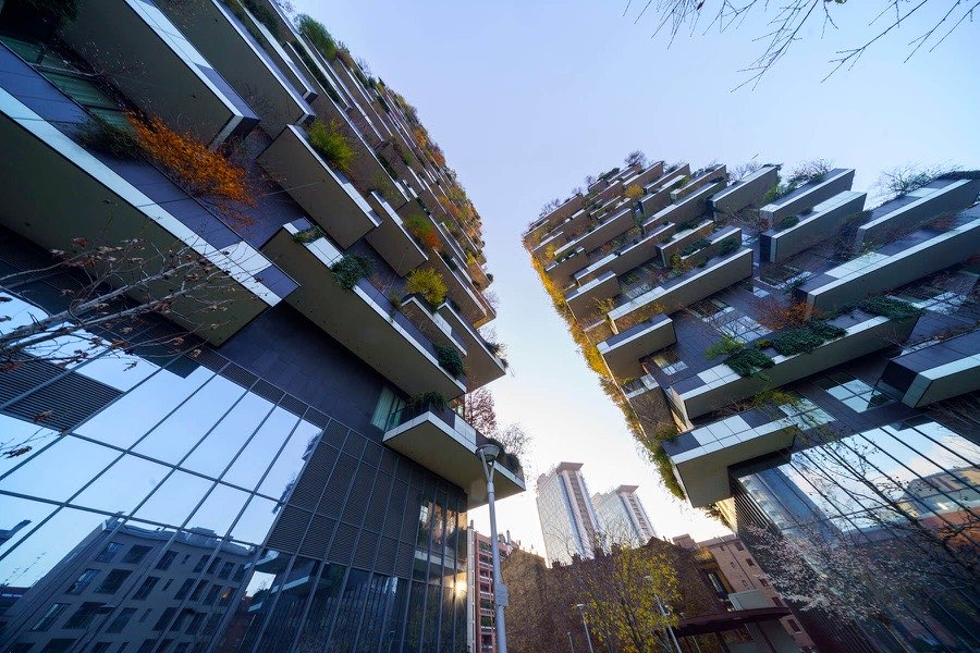 Torres do Bosco Verticale, em Milão, vistas de baixo para cima, com as varandas cobertas de vegetação